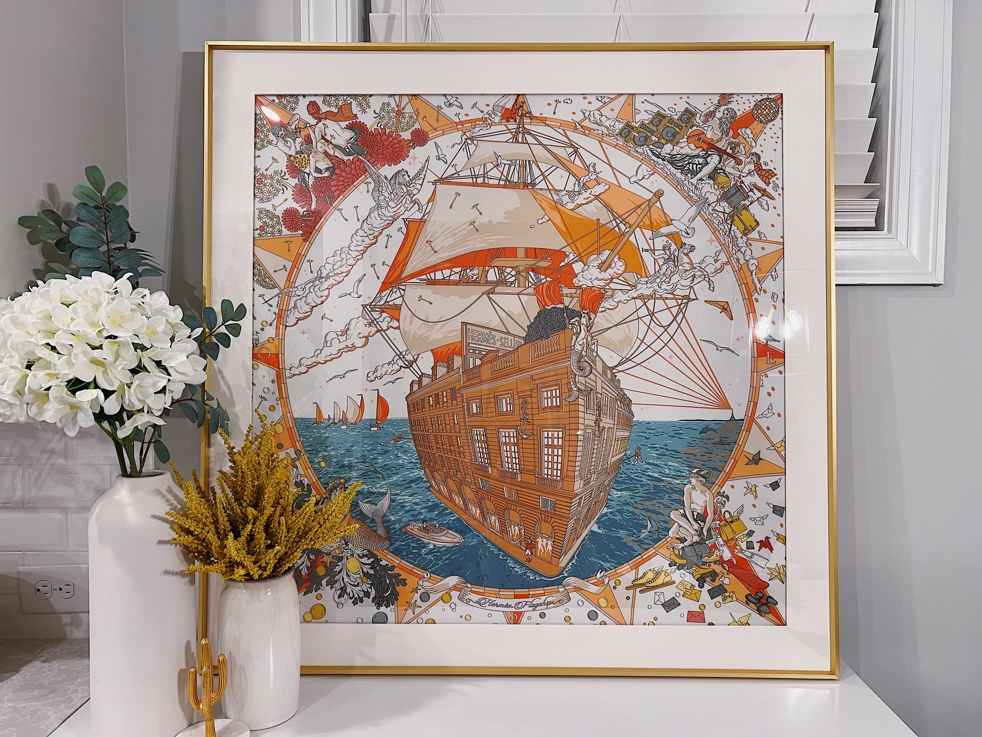Hermes Flagship Scarf 90 framed in gold by Elysian Frame, showcasing elegant silk fabric with intricate logo and border detailing.